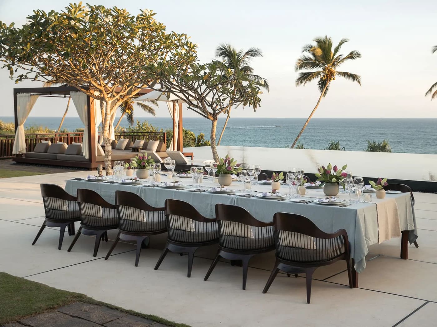 A long table laid for a dinner on a terrace above the sea