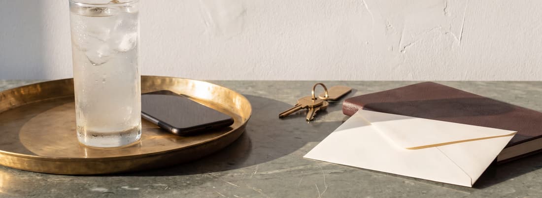 A brass tray with a phone, keys and an envelope