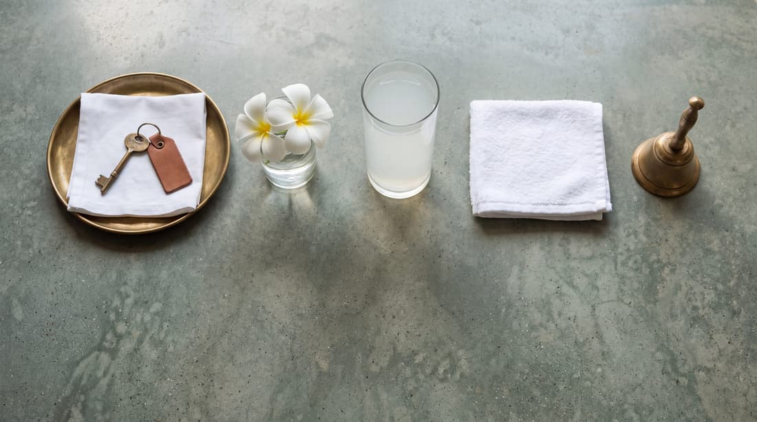 A room key on a napkin, frangipani and a brass bell
