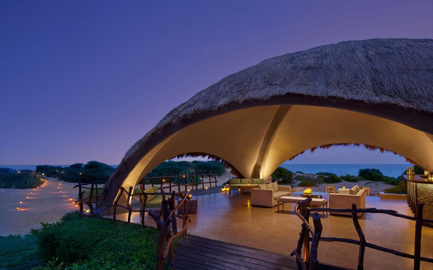 A dining pavilion under a vaulted roof, lit at dusk